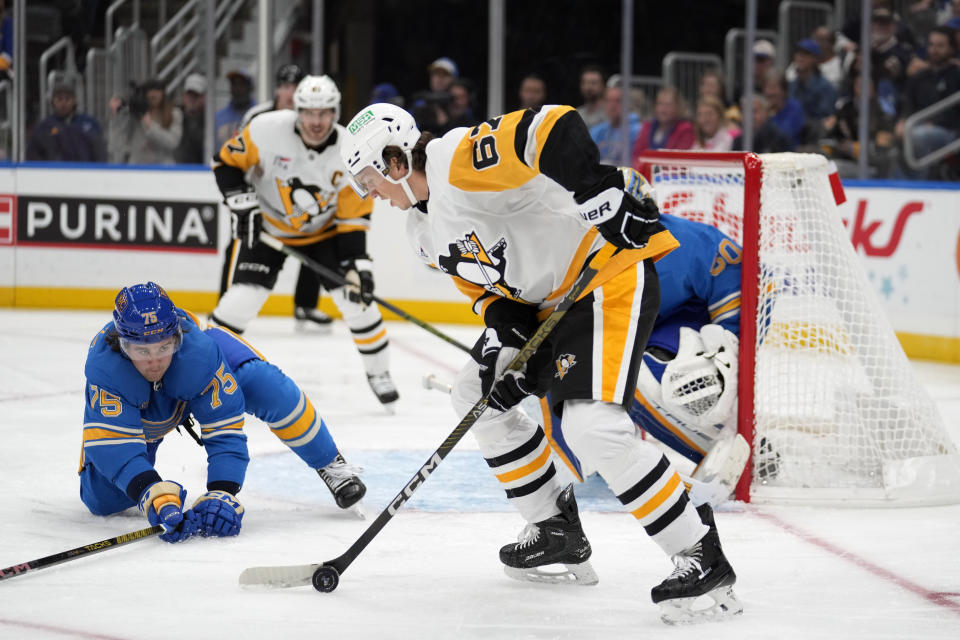 Pittsburgh Penguins' Rickard Rakell (67) controls the puck as St. Louis Blues' Tyler Tucker (75) defends during the third period of an NHL hockey game Saturday, Oct. 21, 2023, in St. Louis. (AP Photo/Jeff Roberson)