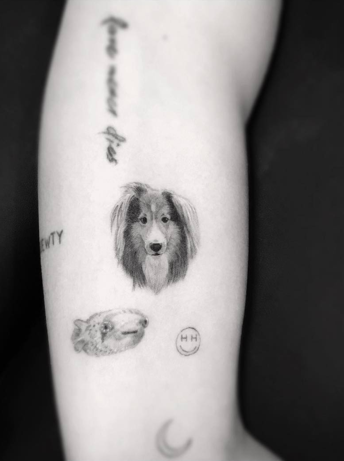 A moon, fish, and a tribute to Emu (her dog) on her left arm