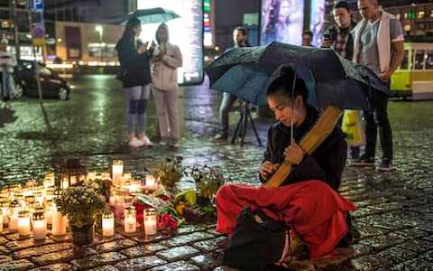 A girl plays a traditional Finnish instrument 'kantele' and singing a traditional lullaby at the site where one person was stabbed to death - Credit: EPA/MARKKU OJALA