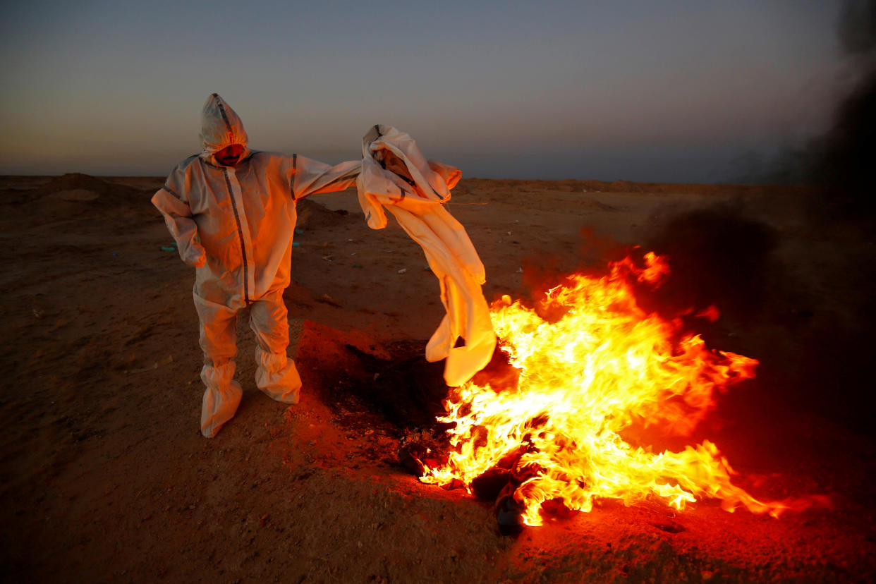 Eine Szene aus dem Irak: Ein ehrenamtlicher Helfer verbrennt Kleider, die zum Begräbnis von an Covid-19 Verstorbenen benutzt wurden (Bild: REUTERS/Alaa al-Marjani)