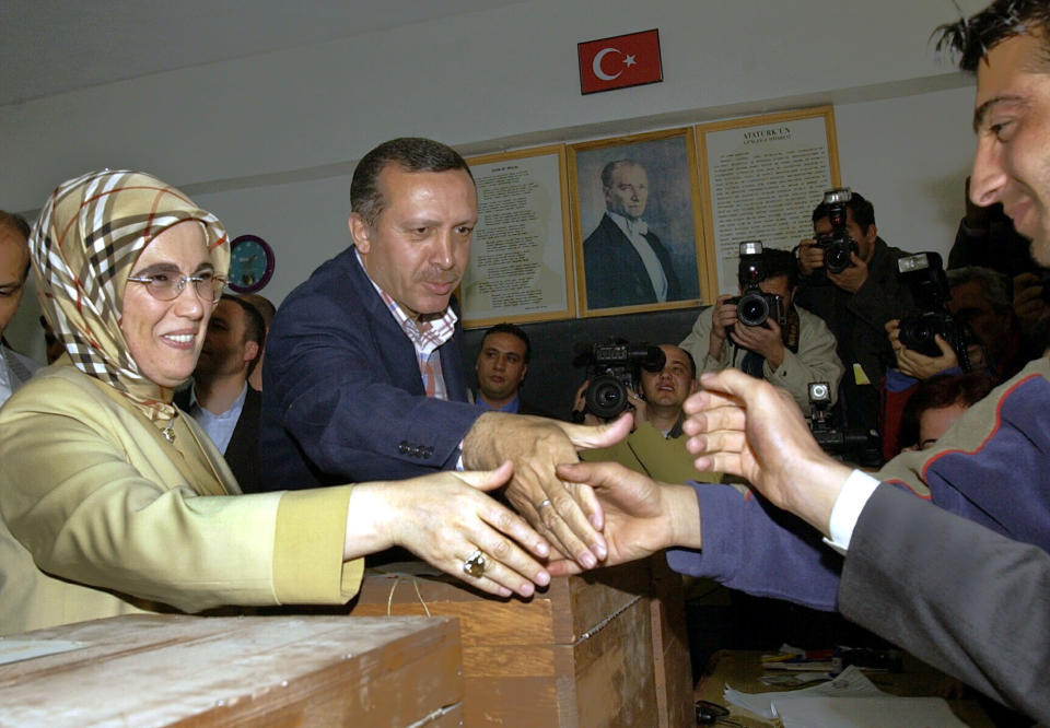 FILE - Turkish Prime Minister Recep Tayyip Erdogan, center, and his wife Emine Erdogan, are welcomed by a polling station official before they cast their votes in the local elections at a primary school in Ankara on March 28, 2004. Erdogan, who is seeking a third term in office as president in elections in May, marks 20 years in office on Tuesday, March 14, 2023. (AP Photo/Burhan Ozbilici, File)