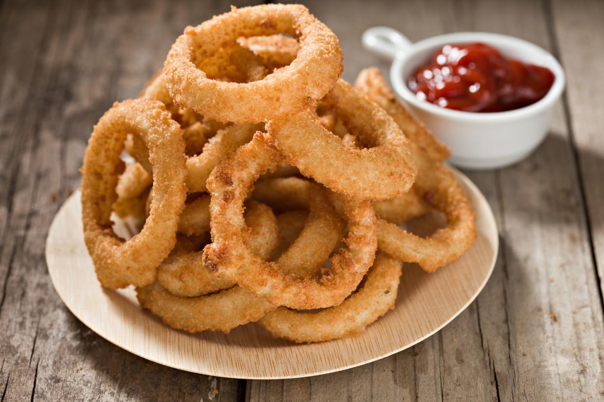 A high angle close up shot of a pile of Onion  Rings stacked on a