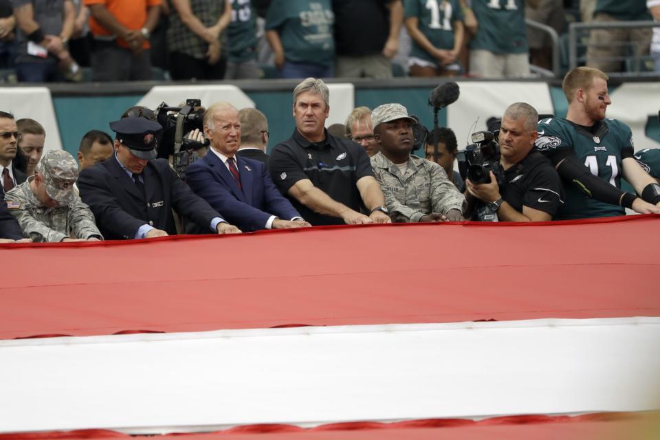 <p>Vice President Joe Biden, left center, and Philadelphia Eagles head coach Doug Pederson, center, hold an American flag before an NFL football game against the Cleveland Browns, Sunday, Sept. 11, 2016, in Philadelphia. The U.S. marked the 15th anniversary of 9/11 on Sunday. (AP Photo/Matt Rourke) </p>
