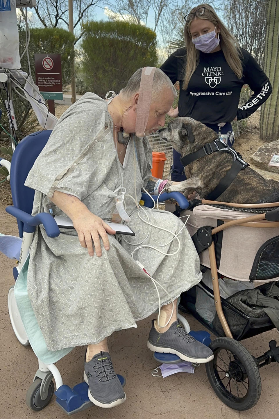 In this photo provided by the Mayo Clinic, Marty Kedian greets his dog, Baxter, on his first trip outside the Mayo Clinic Hospital after his surgery in Phoenix, on March 16, 2024. Kedian regained his voice after surgeons removed his cancerous larynx and, in a pioneering move, immediately replaced it with a donated one. (Mayo Clinic via AP)