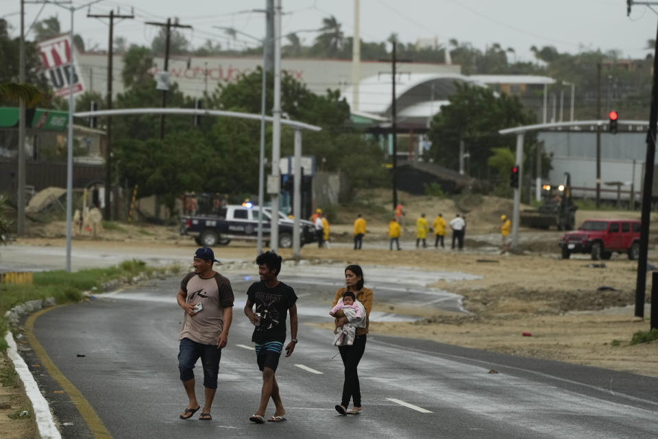 Residents cross near an avenue flooded by the rains of Hurricane Norma in San Jose del Cabo, Mexico, Saturday, Oct. 21, 2023. Norma had weakened and was downgraded to Category 1 on the hurricane wind scale. It was located 25 miles west of Cabo San Lucas storm with winds of 85 mph (140 kmh) and expected to make landfall on Saturday, according to the U.S. (AP Photo/Fernando Llano)