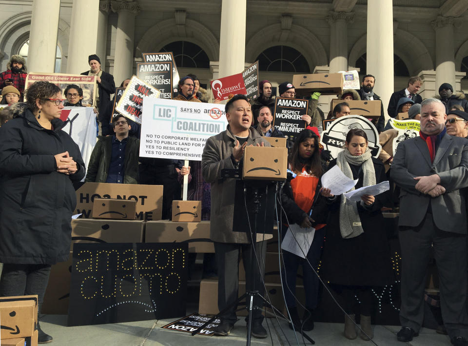 FILE - In this Dec. 12, 2018 file photo, New York State Assemblyman Ron Kim, center, speaks at a rally opposing New York's deal with Amazon on the steps of New York's City Hall. Those opposed to the new Amazon campus had a long list of grievances: the deal was done secretively; Amazon didn’t need nearly $3 billion in tax incentives; and rising rents could push people out of the neighborhood. (AP Photo/Karen Matthews, File)