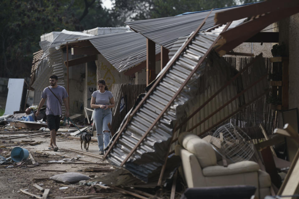 Residents of the kibbutz Kfar Azza walk past destroyed houses near the Gaza Strip, Israel, Monday, Nov. 13, 2023. The kibbutz was attacked during the Hamas cross-border attack on Oct. 7, killing and capturing members of its community. (AP Photo/Leo Correa)