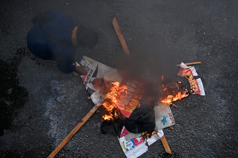 Un opositor al gobierno del presidente venezolano Nicolás Maduro quema carteles de la campaña de Maduro durante una protesta en el barrio de Petare.