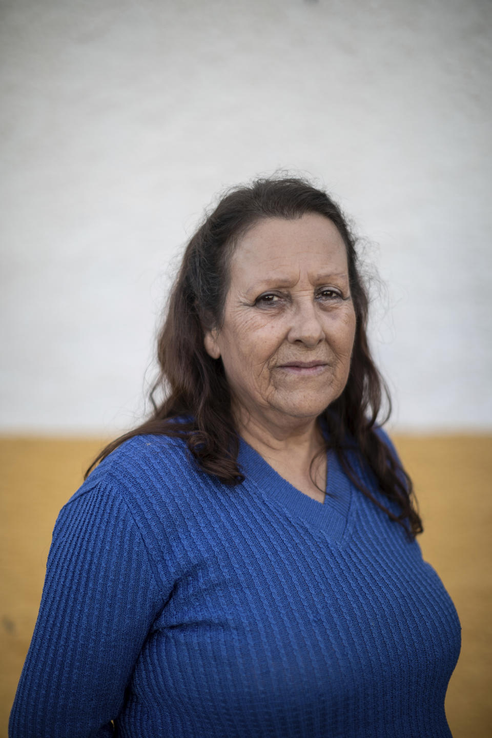 In this April 10, 2019 photo, Marcy Jurado poses for a portrait in La Bienvenida village, central Spain. When the last student left and the school closed, Jurado knew that her village, the heart of the Alcudia valley in central Spain, was about to stop beating. One by one, gone were also the health center, the church and the local bar, the valley's soul. "That's when we knew there was no way back," the 64 year-old said looking down to the empty square of La Bienvenida. (AP Photo/Bernat Armangue)