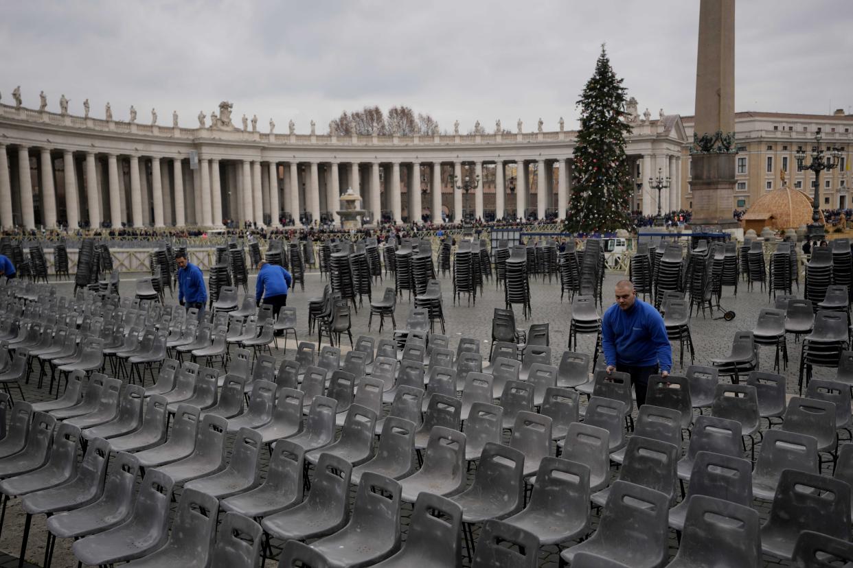 Workers set up chairs as people line up to enter Saint Peter's Basilica at the Vatican where late Pope Benedict XVI is being laid in state at The Vatican, Monday, Jan. 2, 2023. Benedict XVI, the German theologian who will be remembered as the first pope in 600 years to resign, has died, the Vatican announced Saturday. He was 95.(AP Photo/Ben Curtis)