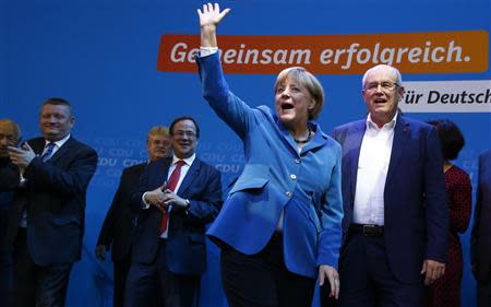 German Chancellor and leader of the Christian Democratic Union (CDU) Angela Merkel waves to supporters next to Volker Kauder, parliamentary floor leader of the CDU (R) as they celebrate with party fellows after first exit polls in the German general election (Bundestagswahl) at the CDU party headquarters in Berlin September 22, 2013. REUTERS/Kai Pfaffenbach