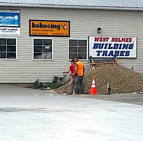 Workers put the finishing touches on the concrete they poured to serve as the base for the ACWHCC Building Trades house project at on the campus of West Holmes High School.