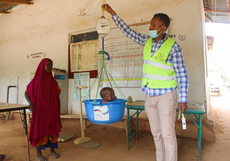 Habiba Mohamed Noor looks on as a Somali health worker screens her son Salad Mukhtar Mohamed for malnutrition, after he arrived at the Dollow hospital in Dollow