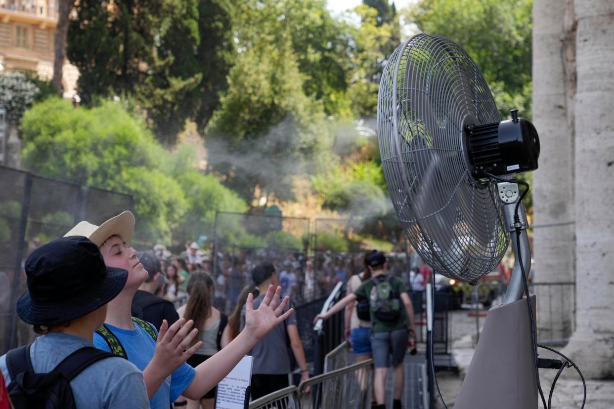 Tourists cool off with a fan in Rome as red alerts issued across the country (Copyright 2023 The Associated Press. All rights reserved.)