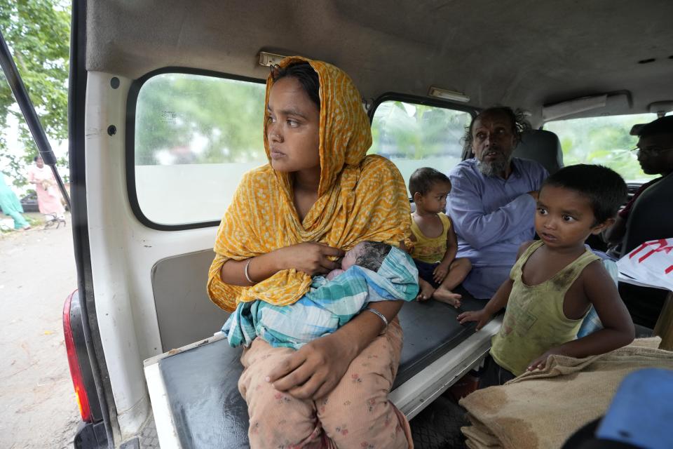 Jahanara Khatoon, de 25 años, da de mamar a su hija recién nacida, nacida en un barco sobre el río Brahmaputra, mientras la familia se sienta en una ambulancia camino del centro médico en el distrito de Morigaon, en el estado nororiental indio de Assam, el miércoles 3 de julio de 2024. (AP Foto/Anupam Nath)
