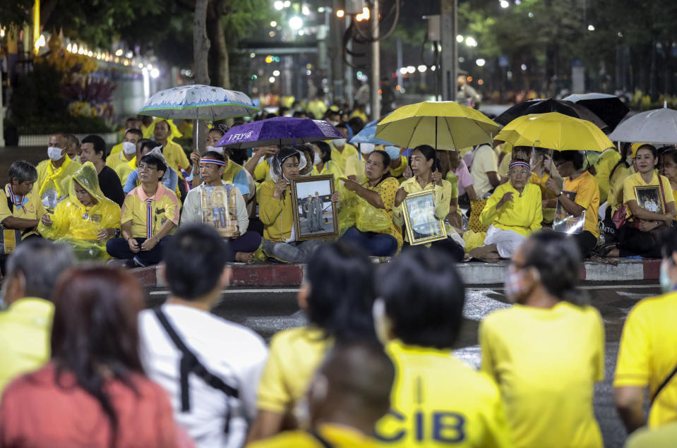 Supporters of the monarchy hold images of Thailand's King Maha Vajiralongkorn and Queen Suthida, as they wait to see their motorcade near Thammasat University in Bangkok, Thailand, Saturday, Oct. 31, 2020. officiating a graduation ceremony at Thammasat University in Bangkok, Thailand, Saturday, Oct. 31, 2020. Thailand’s king has presided over a university graduation ceremony at a stronghold of a protest movement seeking to reduce the monarchy’s powers, after activists issued a call for students to boycott the event. (AP Photo/Sunti Teapia)