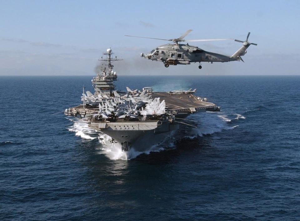 An HH-60H Seahawk helicopter crosses the bow of John F. Kennedy as the carrier battle group arrived in the Mediterranean Sea.