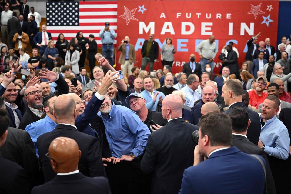 October 27, 2022: US President Joe Biden (L) takes pictures with attendees during an event on Microns plan to invest in CHIPS manufacturing, at the SRC Arena in Syracuse, New York.