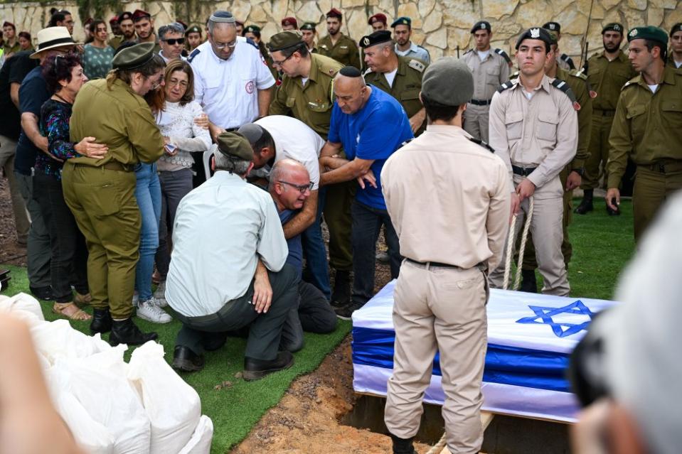 The father of Valentin (Eli) Ghnassia, 23, who was killed in an attack by Hamas militants at Kibbutz Be’eeri near the Israeli border with the Gaza Strip cries next to the casket before it is lowered during his funeral in Jerusalem on Oct. 12.<span class="copyright">Alexi J. Rosenfeld—Getty Images</span>