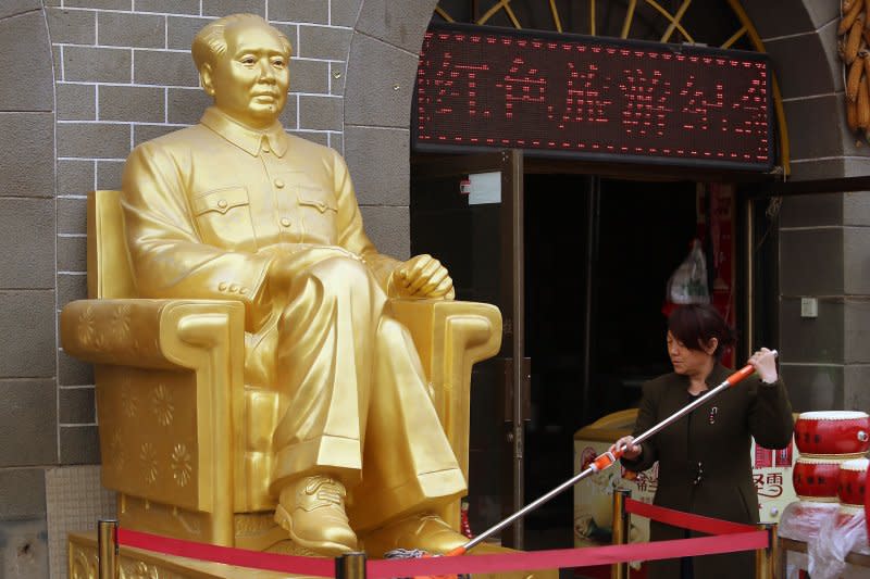 A woman cleans a golden statue of former Helmsman Mao Zedong sitting in front of a communist-themed souvenir shop at a China Revolution tourist site in Yan'an, Shaanxi Province on April 5. On September 9, 1976, Mao died at age 82. File Photo by Stephen Shaver/UPI