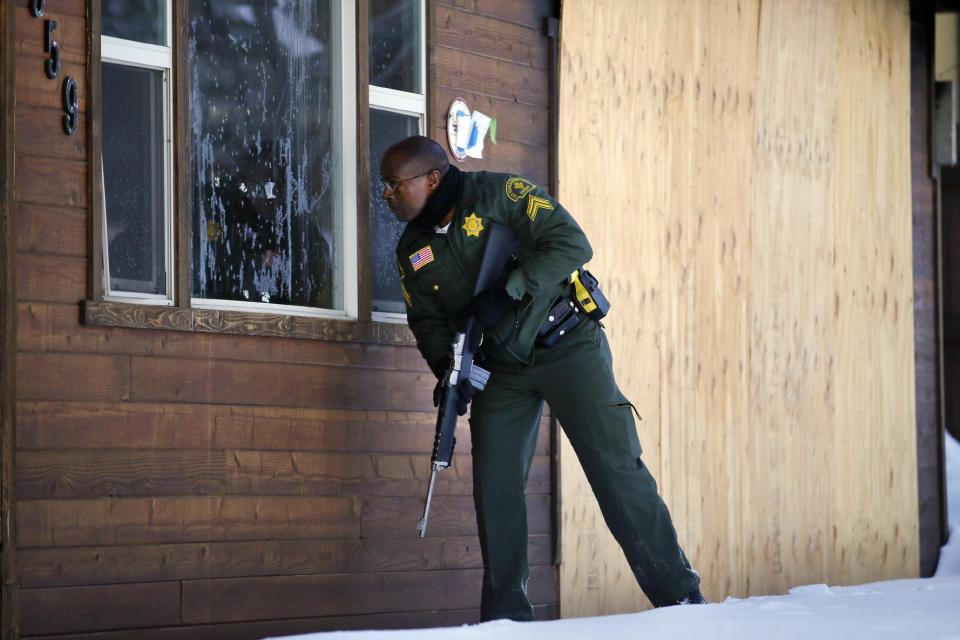 FILE - In this Sunday, Feb. 10, 2013, file photo, San Bernardino County Sheriff's officer Ken Owens searches a home for the former Los Angeles police officer Christopher Dorner in Big Bear Lake, Calif. Eight Los Angeles police officers who mistakenly riddled a pickup truck with bullets during a manhunt for cop-turned-killer Christopher Dorner last year will be allowed to return to the field after they get additional training, Police Chief Charlie Beck said. (AP Photo/Jae C. Hong, File)