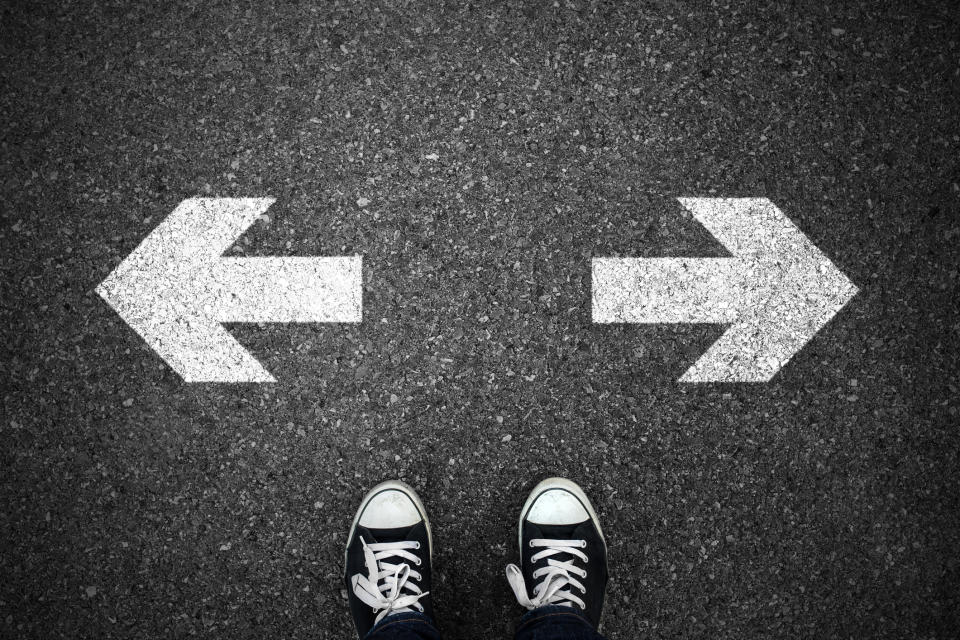 Overhead view of two sneakers in front of arrows painted on the ground that point left and right