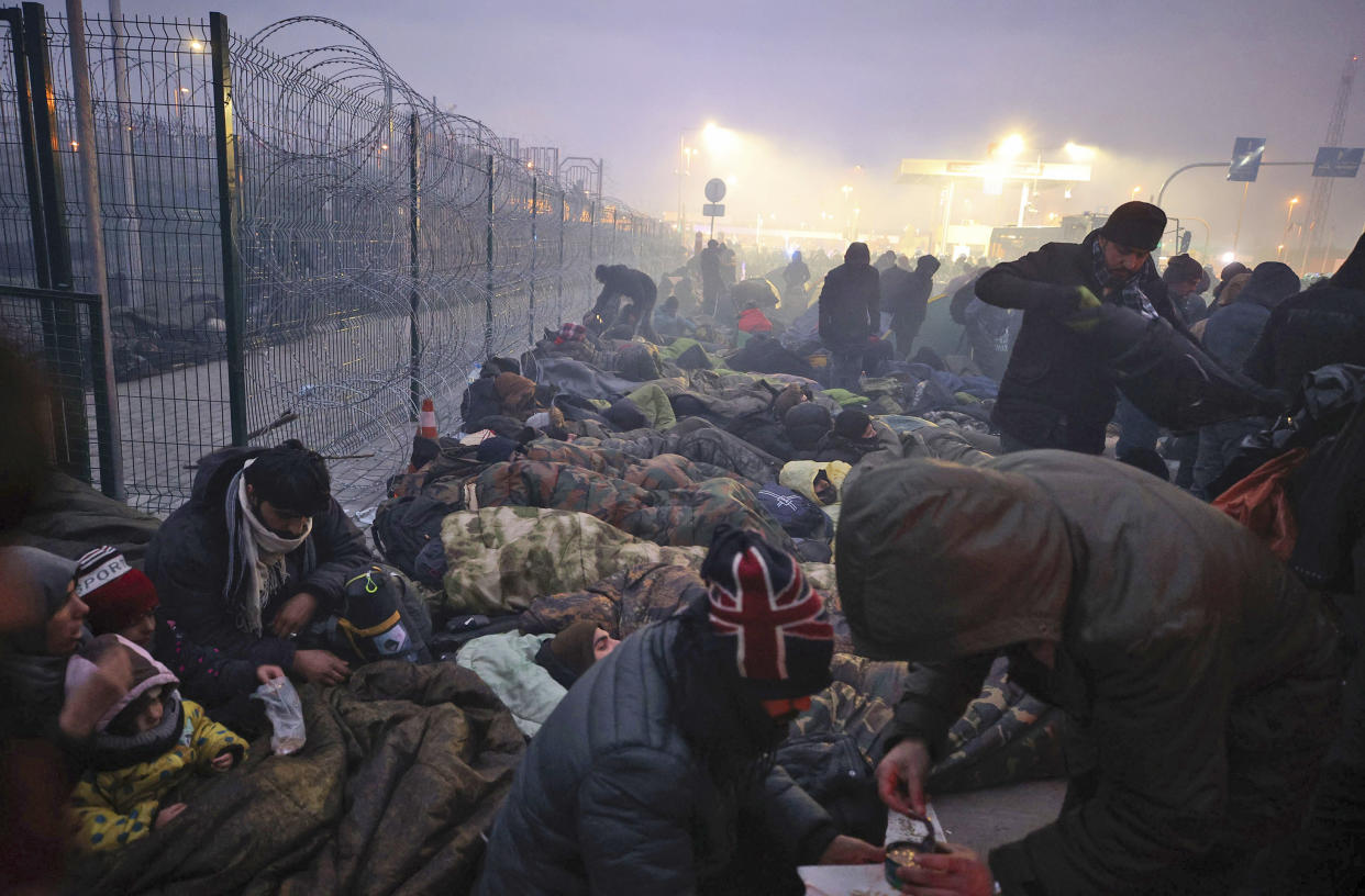 Migrants from the Middle East and elsewhere gather at the checkpoint "Kuznitsa" at the Belarus-Poland border near Grodno, Belarus, on Monday, Nov. 15, 2021. The EU is calling for humanitarian aid as up to 4,000 migrants are stuck in makeshift camps in freezing weather in Belarus while Poland has reinforced its border with 15,000 soldiers, in addition to border guards and police. (Leonid Shcheglov/BelTA via AP)