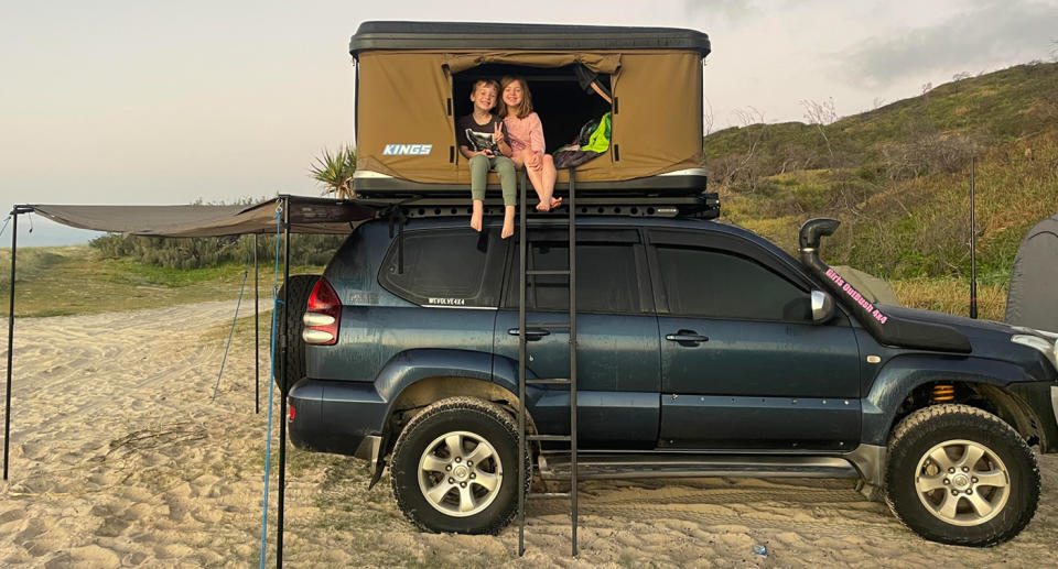 A photo of Nicole's two children sitting in the tent top above her car.