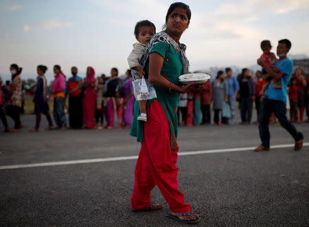 A woman holding her child receives food, distributed by charity group Khalsa Aid to the survivors of the earthquakes, in Kathmandu, Nepal May 14, 2015. REUTERS/Ahmad Masood