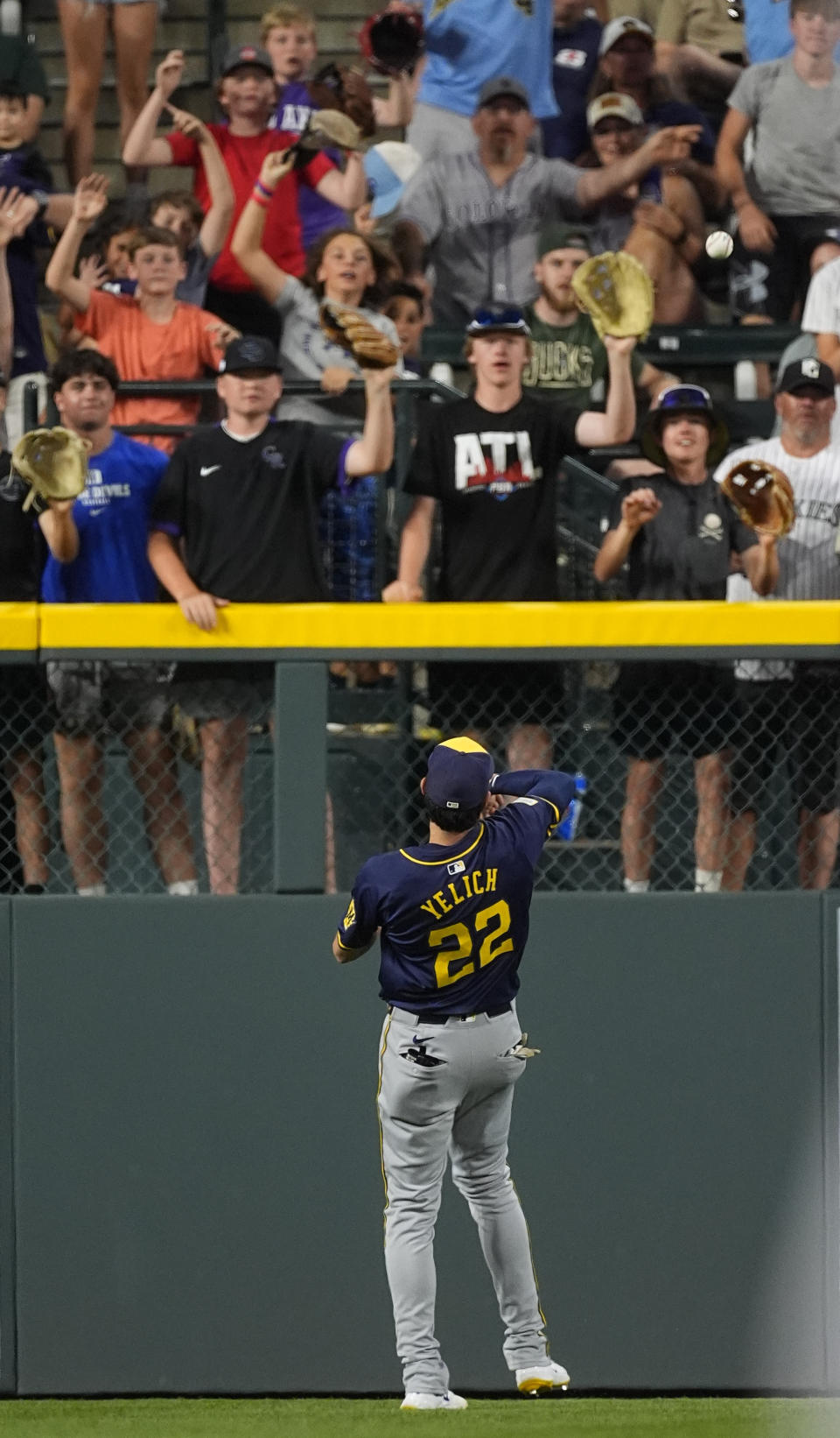 Milwaukee Brewers left fielder Christian Yelich tosses a ball to fans in the eighth inning of a baseball game against the Colorado Rockies, Wednesday, July 3, 2024, in Denver. (AP Photo/David Zalubowski)