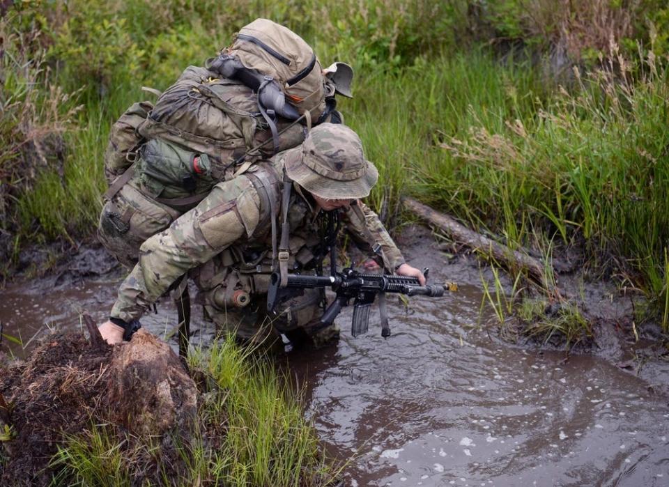 Special Forces candidates assigned to the U.S. Army John F. Kennedy Special Warfare Center and School move through a water obstacle May 27, 2023, during the final phase of field training known as Robin Sage near Hoffman, North Carolina.