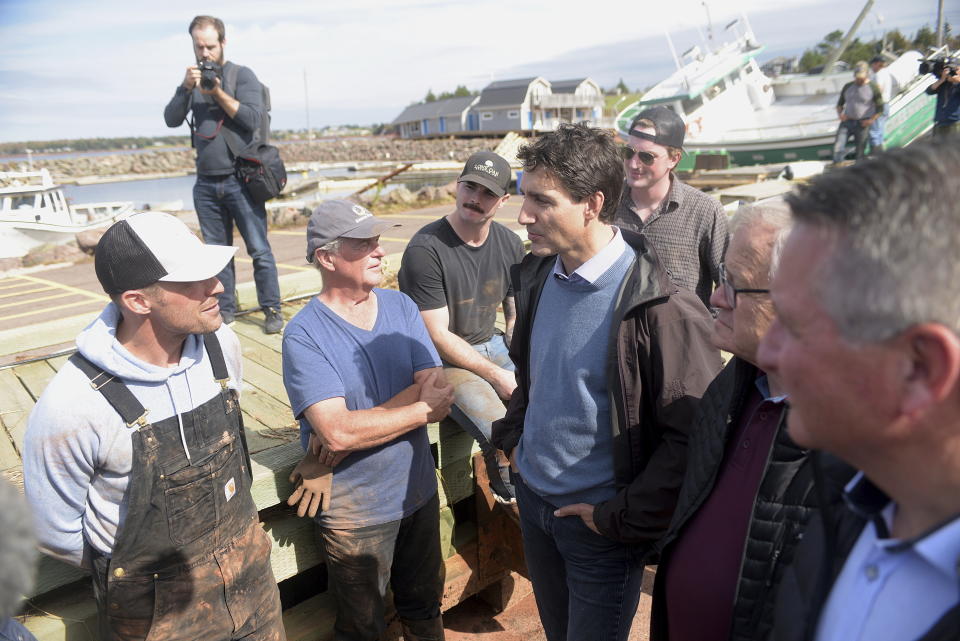 Canadian Prime Minister Justin Trudeau speaks speaks with Mitch Jollimore, left, lobster fisherman and business owner of Stanley's fish and chips and Basin View Seafood as he visits Stanley Bridge, Prince Edward Island, Tuesday, Sept. 27, 2022, to see the damage done by post-tropical storm Fiona. (Brian McInnis/The Canadian Press via AP)