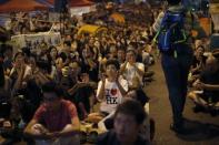 Pro-democracy protestors applaud as they watch formal talks between student protest leaders and city officials on a video screen near the government headquarters in Hong Kong October 21, 2014. REUTERS/Carlos Barria