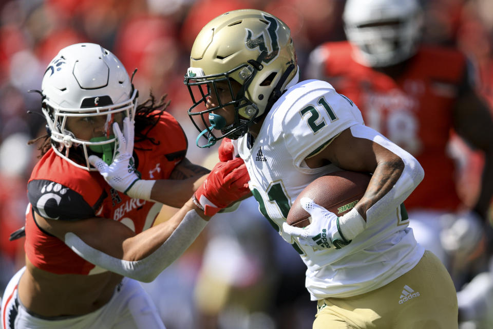 South Florida running back Brian Battie, right, carries the ball as he stiff-arms Cincinnati linebacker Deshawn Pace during the first half of an NCAA college football game, Saturday, Oct. 8, 2022, in Cincinnati. (AP Photo/Aaron Doster)