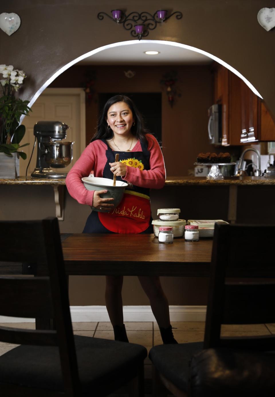 A young woman holds a mixing bowl and spoon.