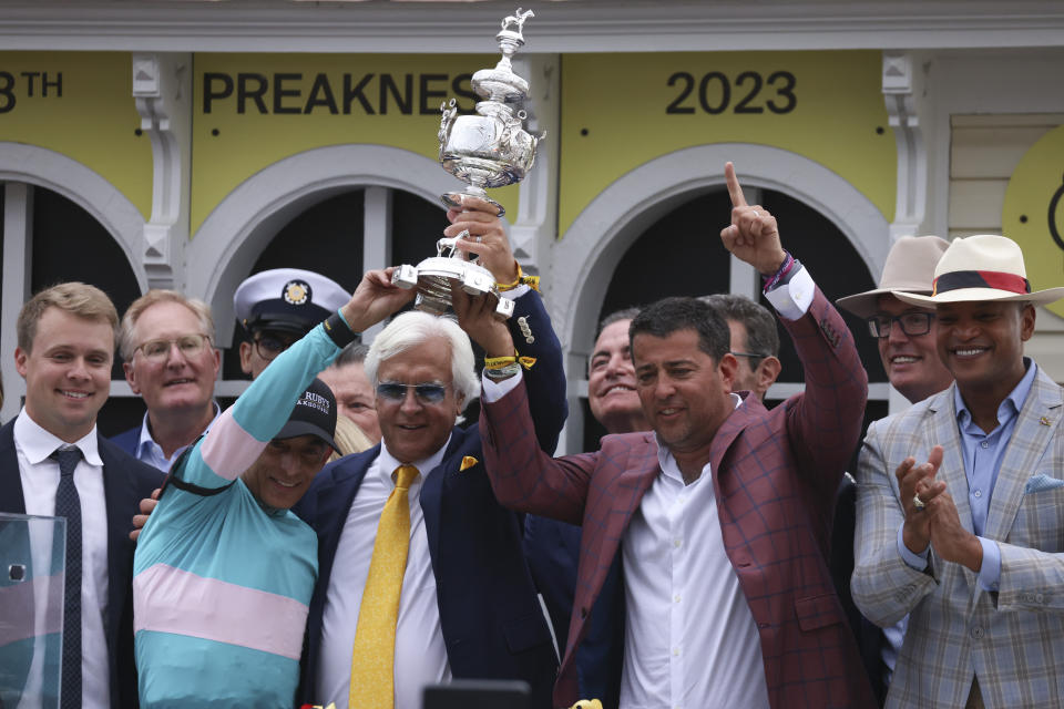 Bob Baffert, center, trainer of National Treasure, and jockey John Velazquez, left, help hoist the Woodland Vase after winning the148th running of the Preakness Stakes horse race at Pimlico Race Course, Saturday, May 20, 2023, in Baltimore. (AP Photo/Julia Nikhinson)