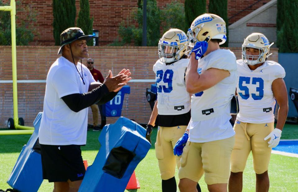 UCLA linebackers coach Ken Norton Jr. talks to linebackers Adam Cohen, Kain Medrano and Darius Muasau.