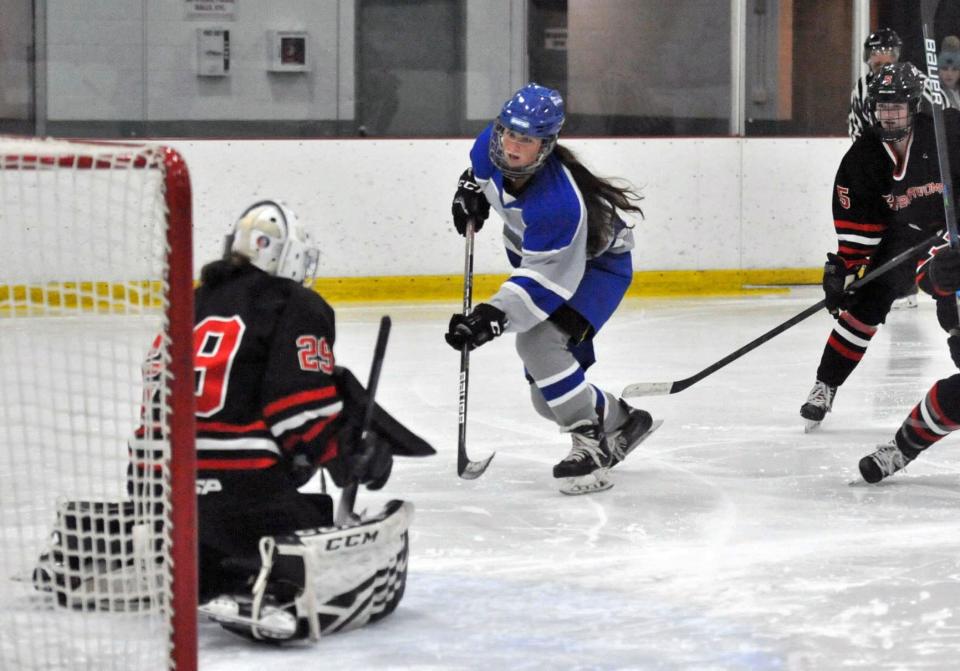 Braintree's Fiona Holland, center, takes a shot on Hingham goalie Isabel McGarr, left, during the Tenney Girls Winter Classic tournament at The Bog in Kingston, Monday, Dec. 26, 2022.