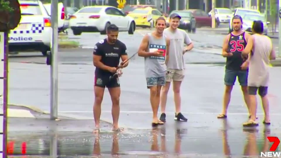 With his mates watching on and cars floating away, this man decided it was time to fish. Source: 7 News