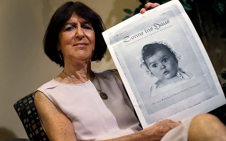 Hessy Levinsons Taft, junto a la icónica portada de la revista nazi Sonne ins Haus de 1935, tras su elección como la bebé aria más hermosa