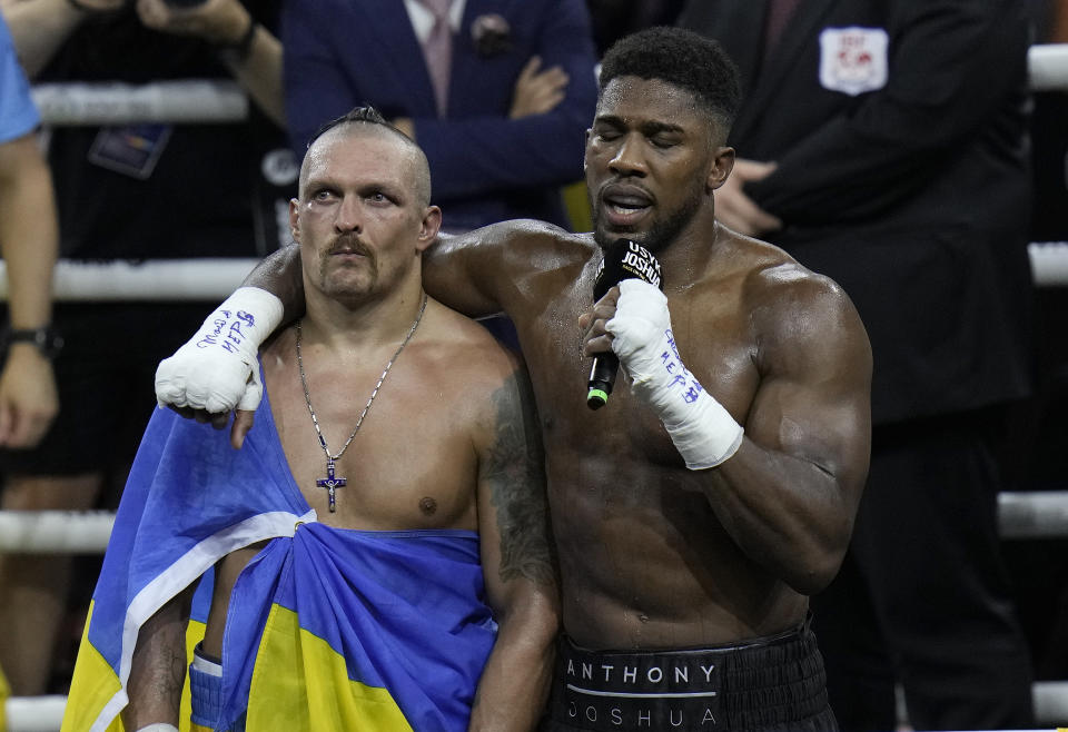 Britain's Anthony Joshua, right, speaks to the crowd after losing to Ukraine's Oleksandr Usyk in their world heavyweight title fight at King Abdullah Sports City in Jeddah, Saudi Arabia, Sunday, Aug. 21, 2022. (AP Photo/Hassan Ammar)