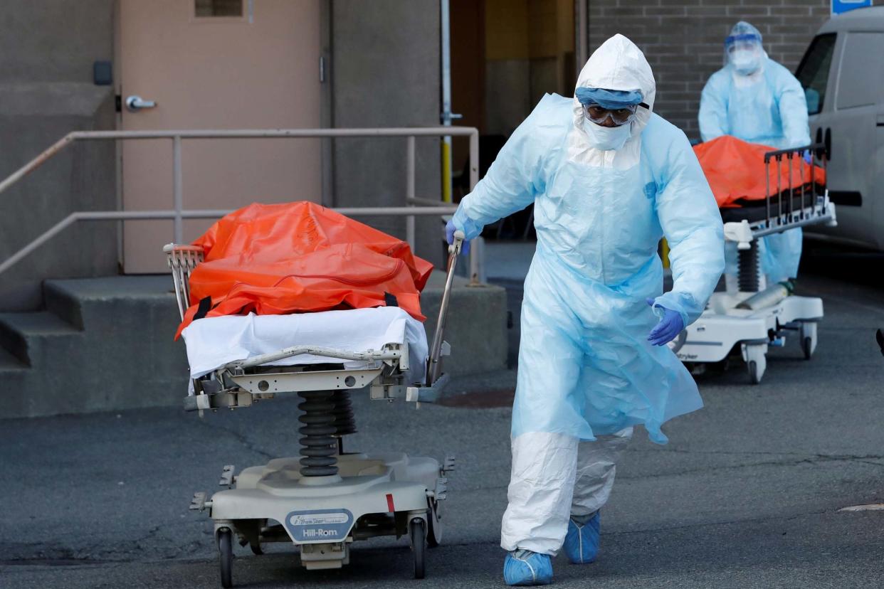 Healthcare workers wheel the bodies of deceased people from the Wyckoff Heights Medical Center in New York: REUTERS