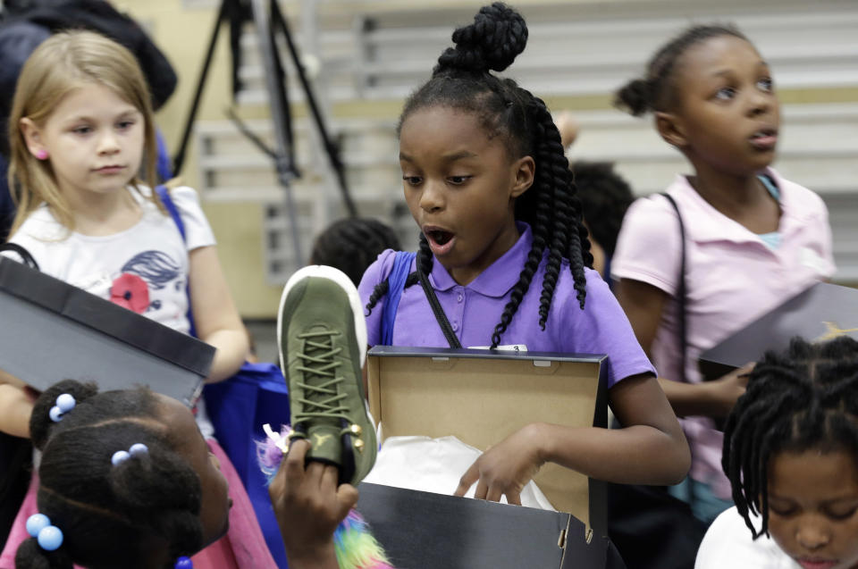 Mondasia Lesine reacts as a friend shows her new shoes presented by Charlotte Hornets owner Michael Jordan following Jordan's visit to the Boys and Girls Club of Wilmington, N.C., Tuesday, Nov. 20, 2018. (AP Photo/Gerry Broome)