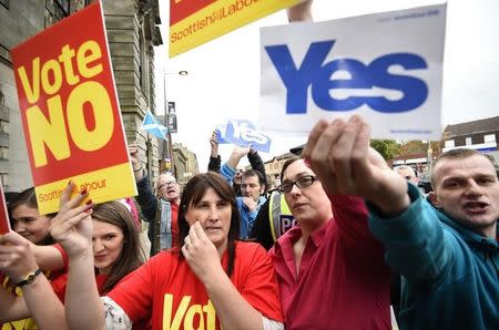 Pro and anti-independence supporters wave posters outside a campaign event in favour of the union in Clydebank, Scotland, September 16, 2014. REUTERS/Dylan Martinez