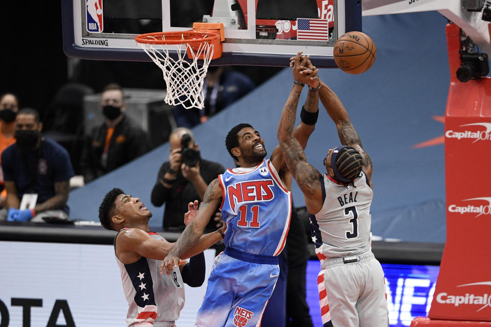Washington Wizards guard Bradley Beal (3) and forward Rui Hachimura, left, battle for the ball against Brooklyn Nets guard Kyrie Irving (11) during the first half of an NBA basketball game, Sunday, Jan. 31, 2021, in Washington. (AP Photo/Nick Wass)