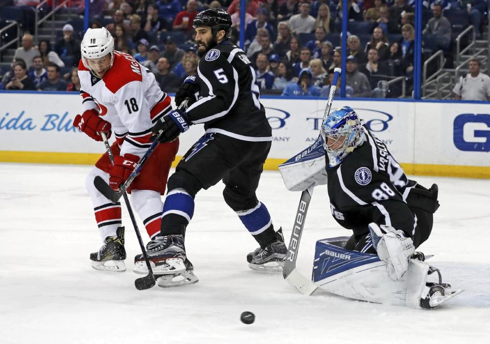 Tampa Bay Lightning goalie Andrei Vasilevskiy, of Russia, makes a save against Carolina Hurricanes' Jay McClement as defenseman Jason Garrison defends during the first period of an NHL hockey game Saturday, Dec. 31, 2016, in Tampa, Fla. (AP Photo/Mike Carlson)