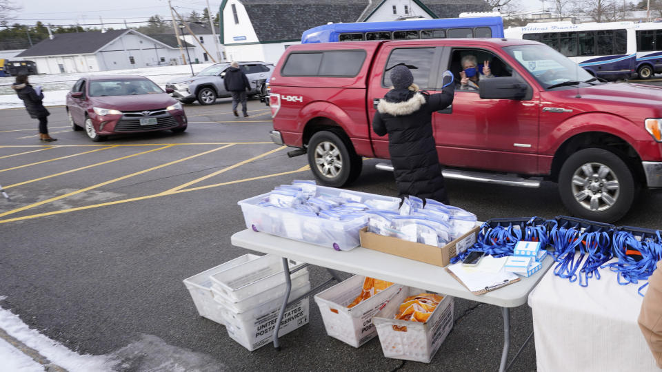 Staff members distribute mobile voting devices to state representatives as they arrive for an outdoor meeting of the New Hampshire House of Representatives in a parking lot, due to the COVID-19 virus outbreak, at the University of New Hampshire Wednesday, Jan. 6, 2021, in Durham, N.H. (AP Photo/Charles Krupa)