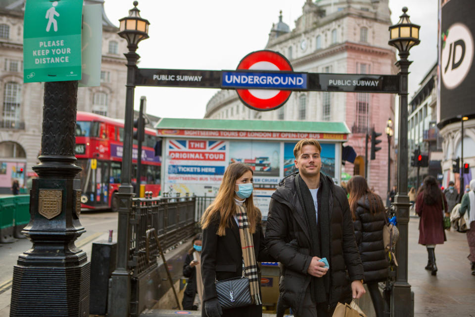 LONDON, UNITED KINGDOM - 2020/12/11: A couple wearing face masks as a precaution against the spread of covid 19 walking out of Piccaadilly underground Station in London. (Photo by Pietro Recchia/SOPA Images/LightRocket via Getty Images)