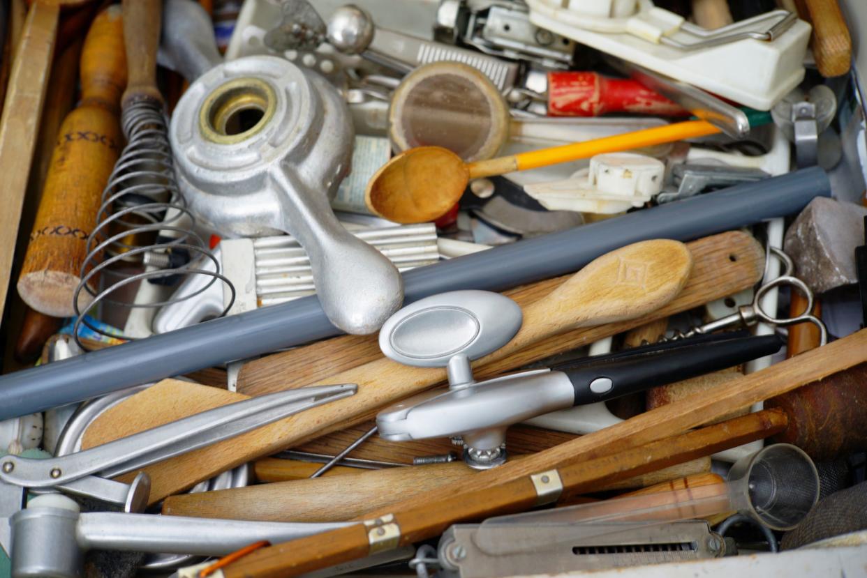 Close up of a kitchen drawer with mess of assorted kitchen tools.