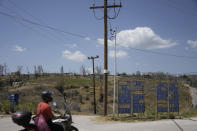 A man with a motorcycle passes Drosopigi village on Parnitha mountain which had been burned in an Aug. 2021 wildfire, in the outskirts of Athens, Friday, Aug. 23, 2024. (AP Photo/Thanassis Stavrakis)